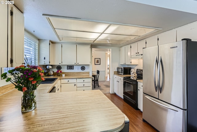 kitchen with white cabinetry, sink, kitchen peninsula, stainless steel appliances, and dark hardwood / wood-style floors