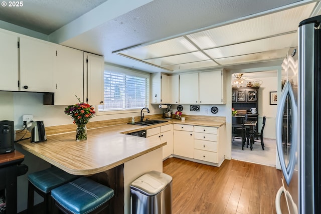 kitchen with sink, white cabinetry, and stainless steel refrigerator