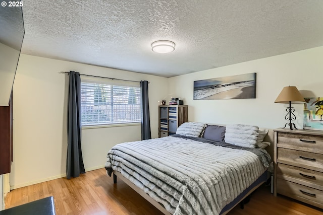 bedroom with light hardwood / wood-style flooring and a textured ceiling