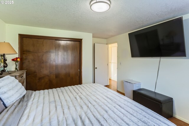 bedroom featuring hardwood / wood-style flooring, a textured ceiling, and a closet