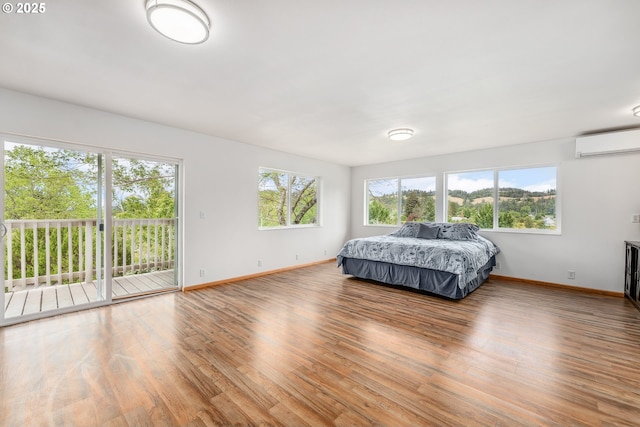 250 Valley View Rd, Sutherlin, OR 97479 - bedroom with a wall unit AC, baseboards, access to outside, and wood finished floors