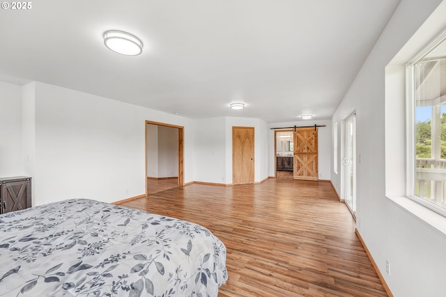 250 Valley View Rd, Sutherlin, OR 97479 - bedroom with a barn door, baseboards, and light wood-type flooring