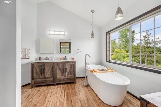 250 Valley View Rd, Sutherlin, OR 97479 - bathroom featuring wood finished floors, double vanity, a soaking tub, baseboards, and high vaulted ceiling