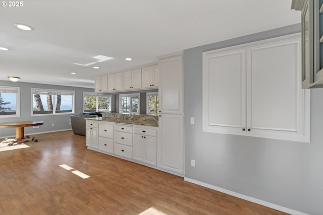 kitchen featuring recessed lighting, light wood-style flooring, white cabinets, a peninsula, and baseboards