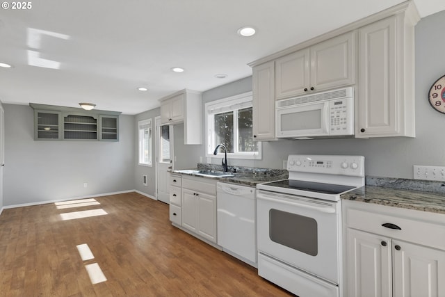 kitchen with recessed lighting, white appliances, wood finished floors, a sink, and baseboards