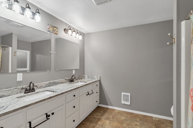 bathroom featuring double vanity, a sink, visible vents, and baseboards