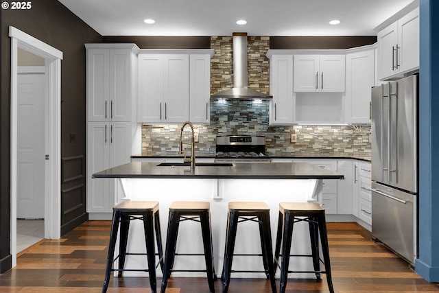 5416 Wales Dr, Eugene, OR 97402 - kitchen featuring appliances with stainless steel finishes, wall chimney range hood, dark countertops, dark wood-style floors, and recessed lighting