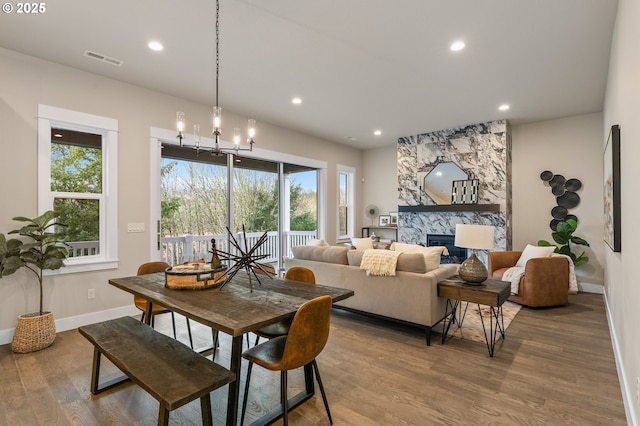 dining room featuring hardwood / wood-style floors, a fireplace, and a chandelier