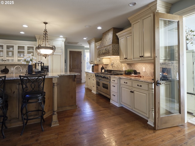 kitchen featuring premium range hood, light stone countertops, range with two ovens, and pendant lighting