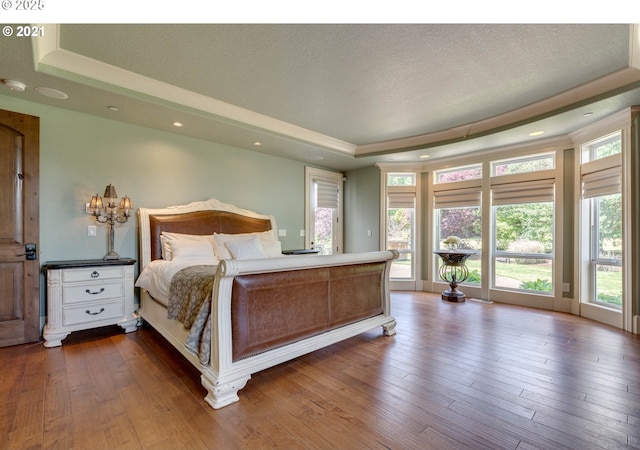 bedroom featuring dark wood-type flooring, a tray ceiling, and a textured ceiling