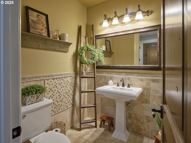 bathroom with tile patterned floors, toilet, sink, and tile walls