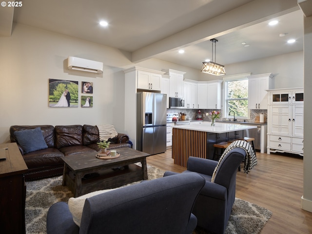 living room with beamed ceiling, a wall mounted air conditioner, sink, and wood-type flooring