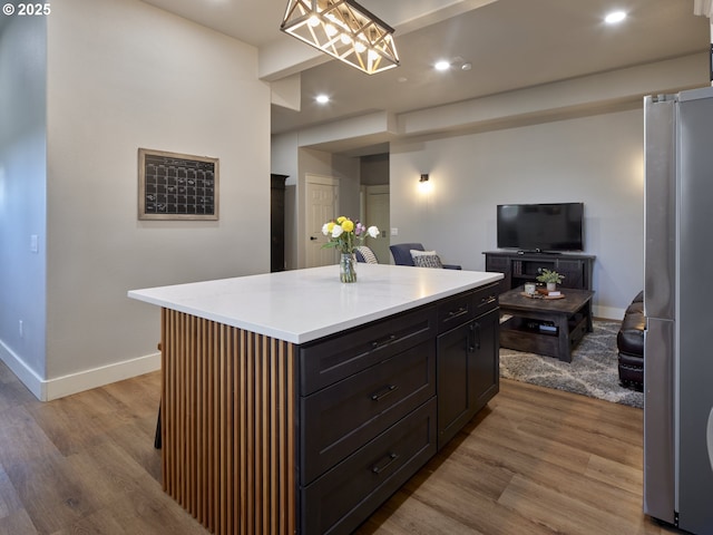 kitchen featuring a kitchen island, pendant lighting, stainless steel fridge, and light hardwood / wood-style floors