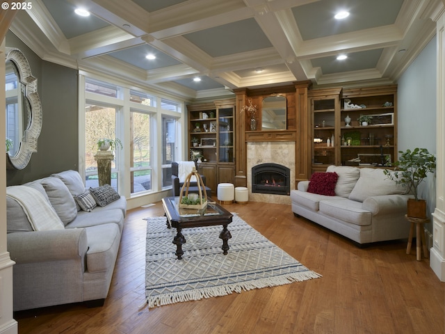 living room with crown molding, built in features, a tile fireplace, and beamed ceiling