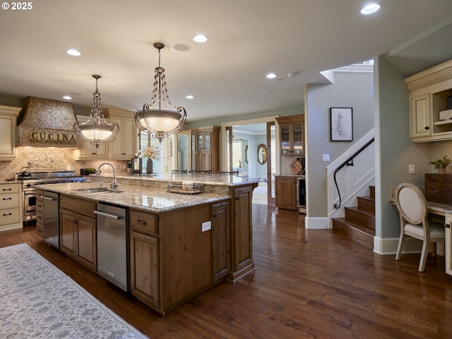 kitchen featuring pendant lighting, an island with sink, sink, custom exhaust hood, and dark wood-type flooring