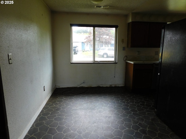 573 SW Harbor Pl, Warrenton, OR 97146 - kitchen with stone floors, a textured ceiling, baseboards, and light countertops