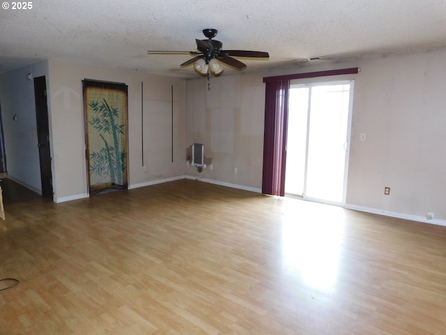 573 SW Harbor Pl, Warrenton, OR 97146 - unfurnished living room featuring light wood-style flooring, ceiling fan, baseboards, and a textured ceiling