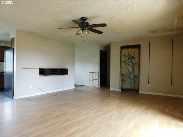 573 SW Harbor Pl, Warrenton, OR 97146 - unfurnished living room with ceiling fan, light wood finished floors, a textured ceiling, and baseboards