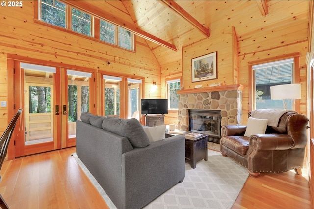 living room with high vaulted ceiling, wood walls, and a healthy amount of sunlight