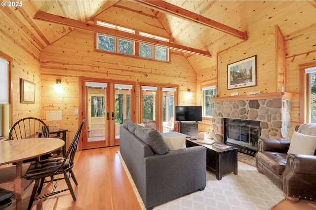 living room featuring beamed ceiling, light wood-style floors, wooden walls, wooden ceiling, and french doors