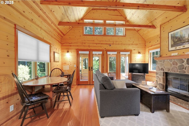living area with wood walls, french doors, light wood finished floors, and beam ceiling
