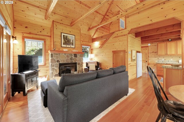 living area featuring visible vents, light wood-style floors, wooden walls, and wooden ceiling