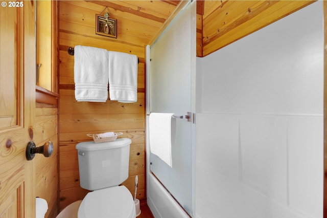 bathroom featuring wood walls, a shower with door, and toilet