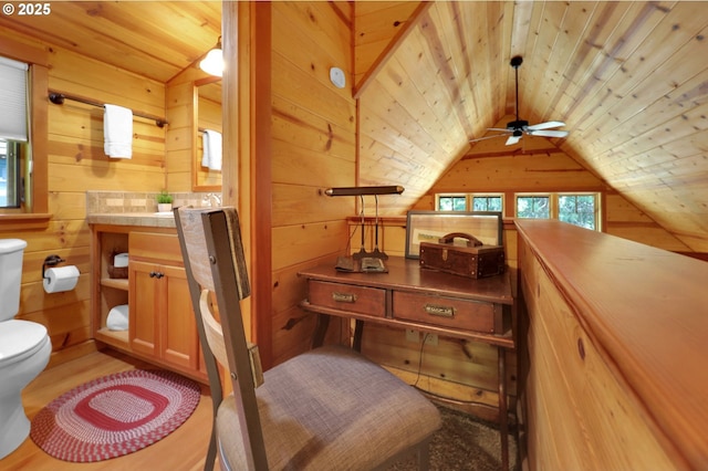 interior space featuring wood ceiling, ceiling fan, vaulted ceiling, toilet, and wooden walls