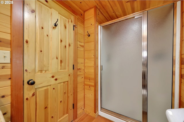 full bathroom with wooden walls, wooden ceiling, a stall shower, and wood finished floors