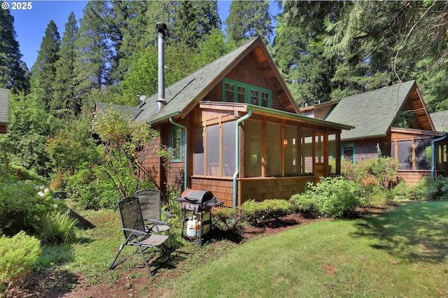 rear view of property with a lawn and a sunroom