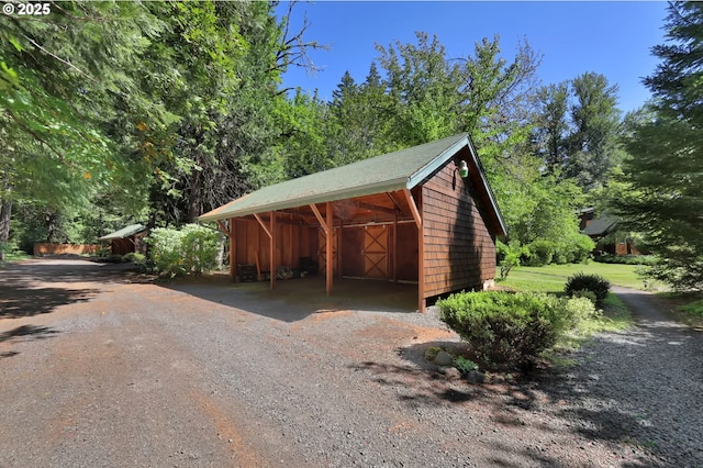 view of outdoor structure with an outbuilding, driveway, and a carport