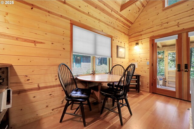 dining space featuring wooden walls, plenty of natural light, and light wood-style flooring