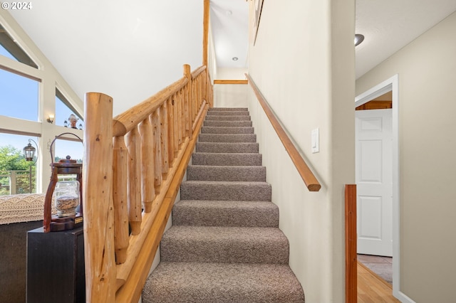 stairway with vaulted ceiling and wood-type flooring