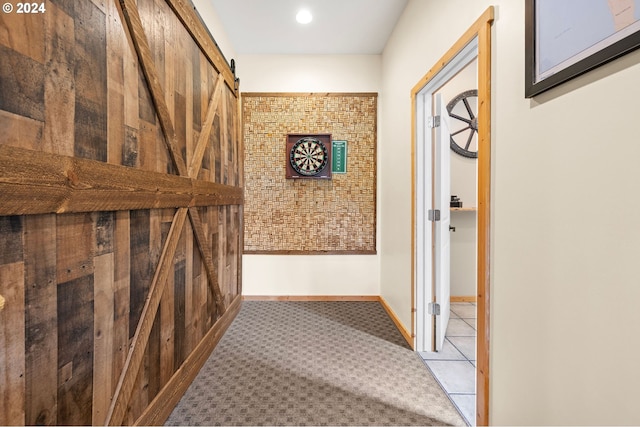 hall with a barn door and light tile patterned floors