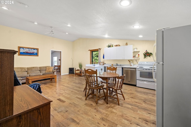 dining area with vaulted ceiling, ceiling fan, and light wood-type flooring