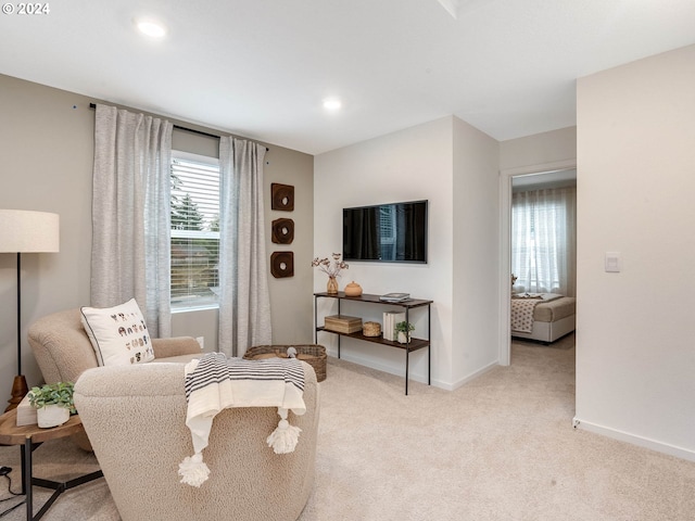 sitting room with baseboards, recessed lighting, and light colored carpet