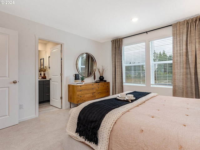 bedroom featuring ensuite bath, baseboards, and light colored carpet