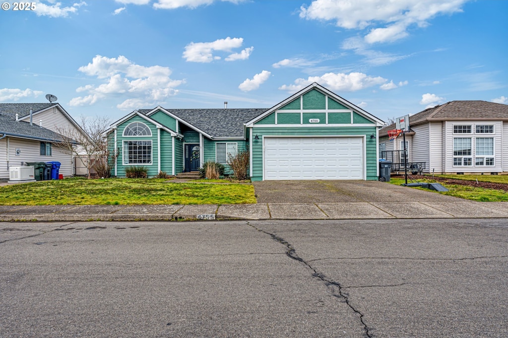 view of front of house featuring a garage, a front yard, and central AC unit