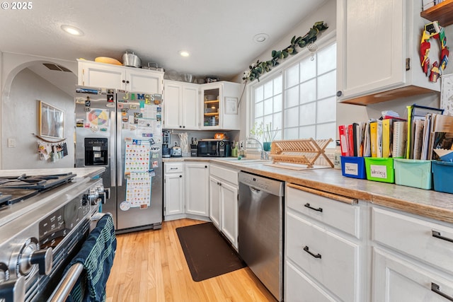 kitchen featuring sink, light hardwood / wood-style floors, white cabinets, and appliances with stainless steel finishes