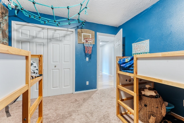 carpeted bedroom featuring a textured ceiling and a closet