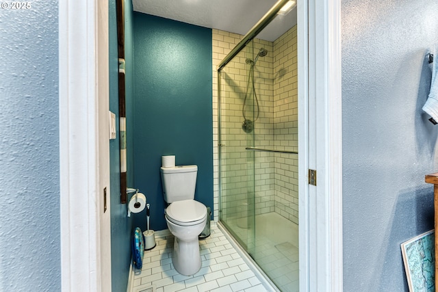 bathroom with a shower with door, tile patterned floors, and toilet