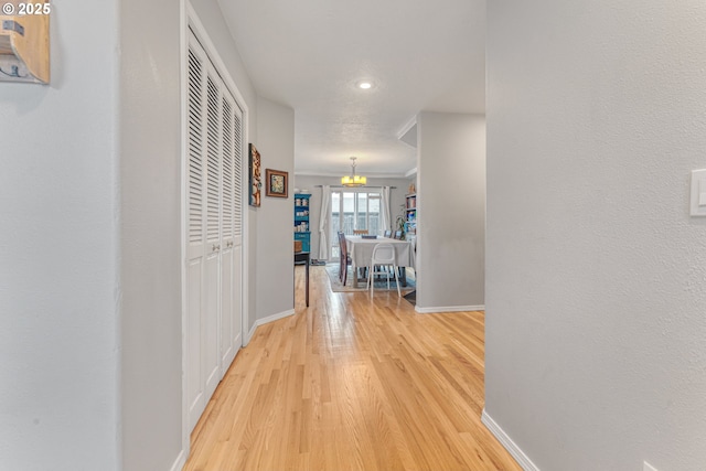 hall with hardwood / wood-style flooring and a chandelier