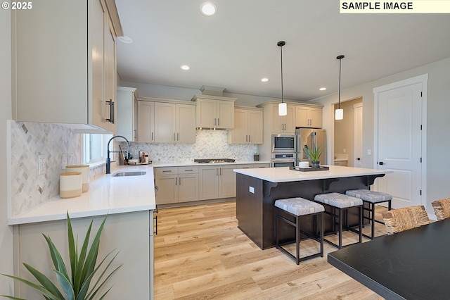 kitchen with a kitchen bar, stainless steel appliances, tasteful backsplash, decorative light fixtures, and sink