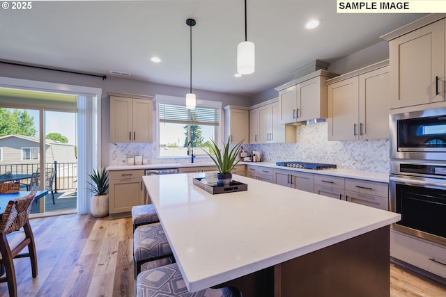 kitchen with a kitchen island, light hardwood / wood-style floors, sink, hanging light fixtures, and a kitchen breakfast bar