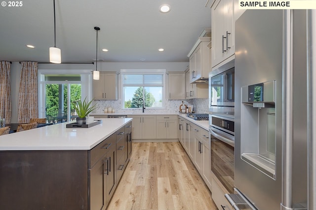 kitchen featuring pendant lighting, a kitchen island, decorative backsplash, a wealth of natural light, and stainless steel appliances