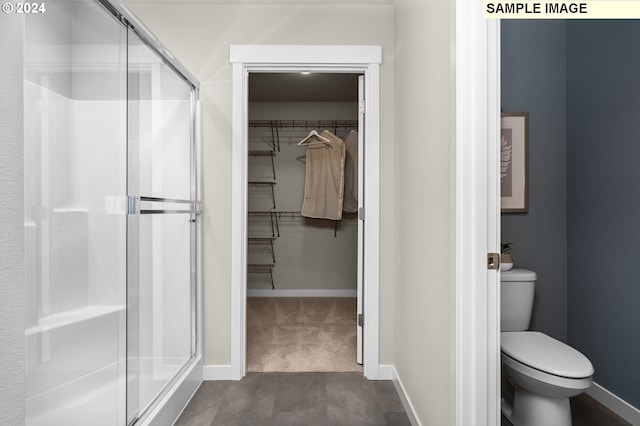 bathroom featuring toilet and a shower with door