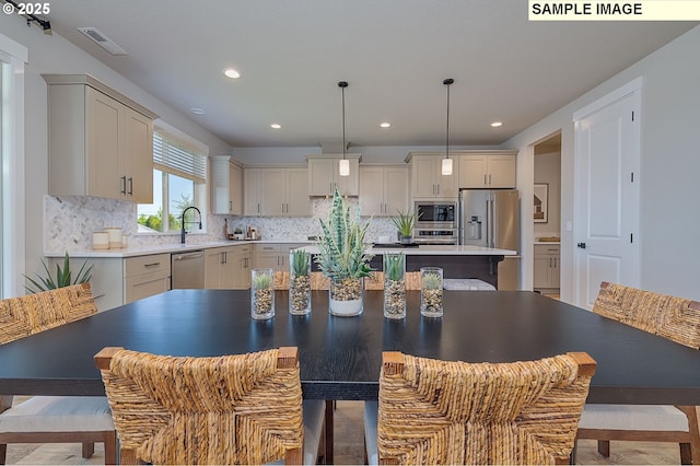 kitchen with a center island, decorative light fixtures, stainless steel appliances, tasteful backsplash, and sink