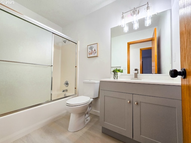 full bathroom with combined bath / shower with glass door, vanity, and toilet