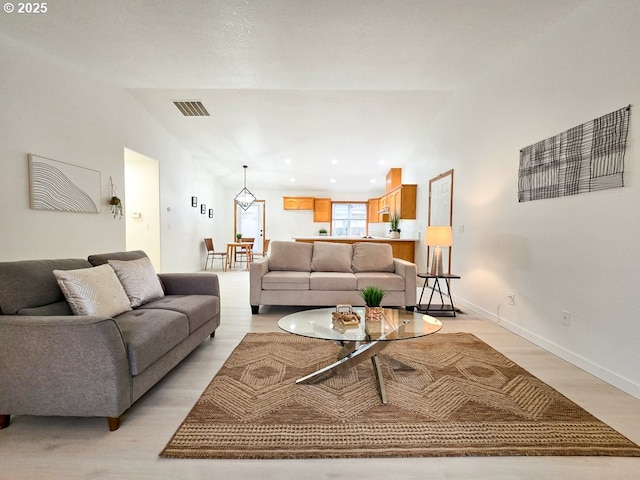 living room featuring baseboards, visible vents, lofted ceiling, light wood-style floors, and recessed lighting