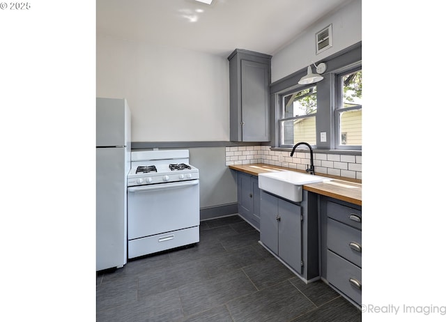 kitchen with wooden counters, white appliances, a sink, gray cabinetry, and decorative backsplash